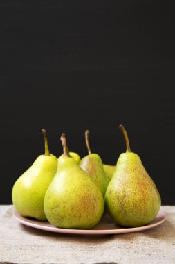 Siyah arka plan, yan görünüm karşı pembe plaka üzerinde lezzetli taze armut. Yakın çekim. Seçici odak. 