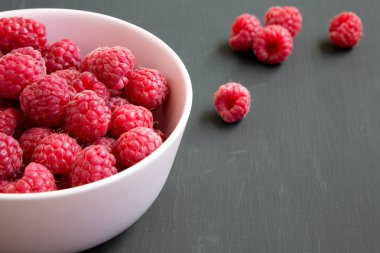 Ahududu koyu ahşap yüzey, yan görünüm üzerinde pembe bir kase. Yakın çekim.