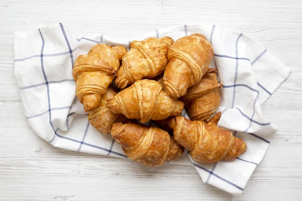 Taze pişmiş kruvasanlar Beyaz ahşap masa, havai görünümü üzerine kumaş üzerinde. Yukarıdan, üstten görünüm, düz yatıyordu. Yakın çekim.