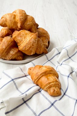Taze pişmiş kruvasanlar Grey Beyaz ahşap arka plan, yan görünüm tabağa yuvarlak. 