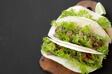 Siyah arka planda, düşük açılı görünüş rustik ahşap tahta üzerinde karides Taco. Meksika mutfağı.