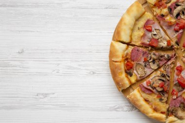 Beyaz ahşap yüzey, havai görünümü üzerinde yuvarlak bambu tahta üzerinde taze pişmiş pizza. Yat, yukarıdan görünüm, top. Metin için yer.