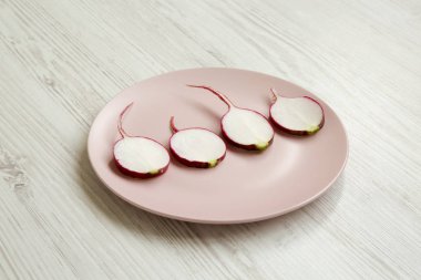 Beyaz ahşap masa, yan görünüm pembe plaka turp dilimleri.