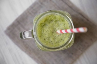 Cam kavanoz yeşil kereviz güler yüzlü beyaz ahşap arka planda, üstten görünüm. Yakın çekim.