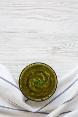 Beyaz ahşap arka planda, üstten görünüm fesleğen pesto kase. Uzay kopyalayın. Düz, tepegöz, yukarıdan yatıyordu.