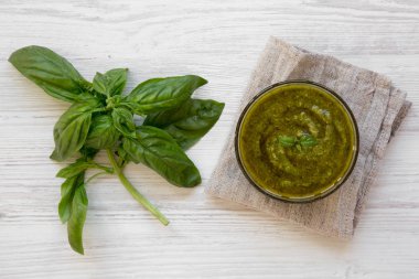 Fesleğen pesto üstten görünüm beyaz tahta masada kase. Düz, tepegöz, yukarıdan yatıyordu.