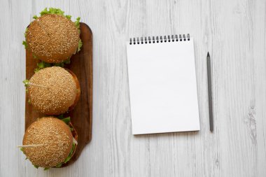 Çizburger ahşap tahta ve üstten görünüm beyaz tahta masada boş not defteri. Üstten, yukarıda. Metin için yer.