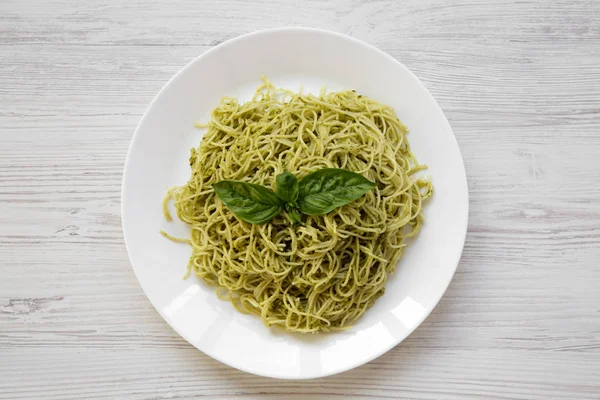Beyaz ahşap masa, ek yükü üzerine pesto soslu makarna spagetti tabak. Üstten görünüm, yat.