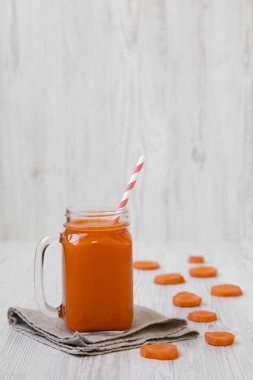 Cam sürahi havuç güler yüzlü beyaz ahşap yüzey, yan görünüm. 