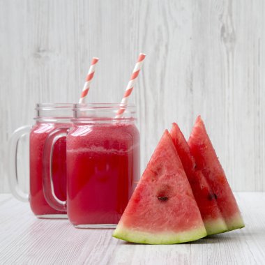 Karpuz güler yüzlü beyaz ahşap yüzey, yan görünüm üzerinde cam kavanozlara ile dilim. Yakın çekim.