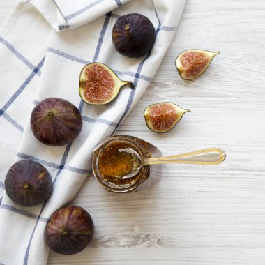 Beyaz ahşap masa, üstten görünüm üzerinde taze incir ve incir reçeli cam kavanoz. Düz, tepegöz, yukarıdan yatıyordu. Yakın çekim.