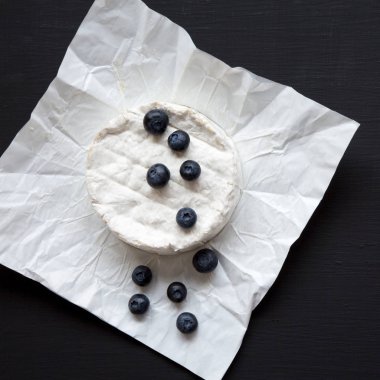 Camembert peyniri siyah arka plan, havai görünümü üzerinde yaban mersini ile. Yiyecek şarap için. Yakın çekim.
