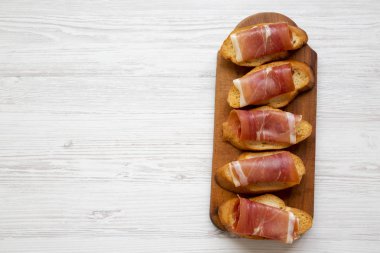 Crostini ile serrano jambonu havai görünümü beyaz tahta masada ahşap tahta üzerinde. Yat, yukarıdan görünüm, top. Boşluk ve metin alanı Kopyala.