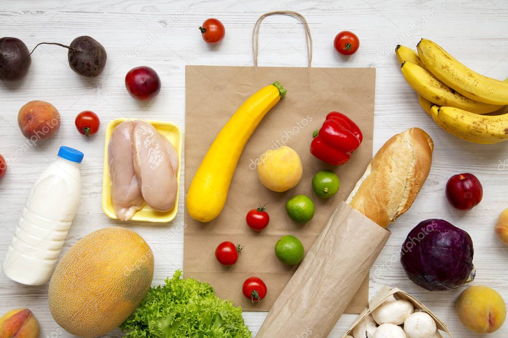 Food bag on white wooden table. Groceries background. Flat lay of fresh fruits, veggies, greens, meat, milk. Top view, overhead, from above. Shopping concept.