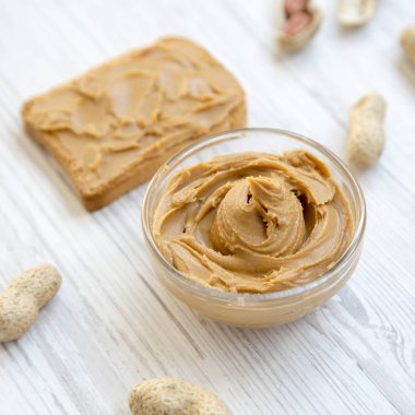 Tost, kase fıstık ezmesi ve fıstık kabukları üzerinde beyaz ahşap bir masa yan görünüm. Yakın çekim.