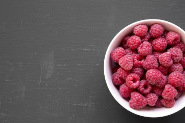 Ahududu siyah arka plan, havai görünümü üzerine pembe kase. Yukarıdan, üstten görünüm, düz yatıyordu. Metin için yer.