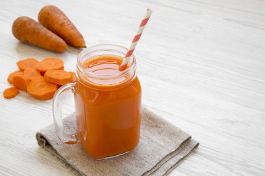 Cam sürahi havuç güler yüzlü bir beyaz tahta masada yakın çekim. Kopya alanı.