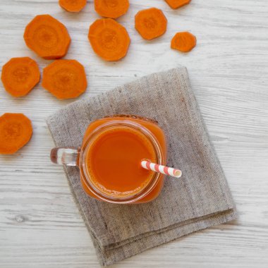 Cam sürahi havuç güler yüzlü beyaz ahşap bir masa üstten görünüm üzerinde. Düz, tepegöz, yukarıdan yatıyordu. 