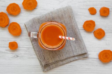 Cam sürahi havuç güler yüzlü beyaz ahşap zemin, havai görünümü üzerinde. Yukarıdan yatıyordu, en iyi görünüm, düz. 