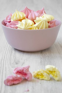 Mini meringues Beyaz ahşap arka plan, yan görünüm üzerinde pembe bir kase. Yakın çekim. 