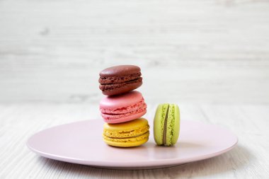 Tatlı ve beyaz ahşap arka plan, yan görünüm üzerinde pembe plaka üzerinde renkli macarons. Yakın çekim. 