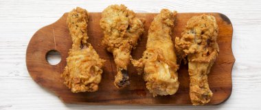 Beyaz ahşap yüzey, en iyi görünümü üzerinde ahşap tahta üzerinde kızarmış tavuk sopaları. Tepegöz, lay, yukarıdan düz. Yakın çekim.