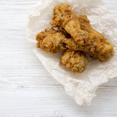 Kızarmış tavuk ldrumsticks kağıt üzerinde beyaz ahşap arka plan, yukarıdan görüntüleyin. Üstten görünüm, ek yükü.