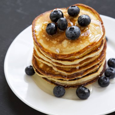 Krep yaban mersini ve koyu arka plan üzerinde beyaz yuvarlak tabakta bal ile yakın çekim. Yan görünüm.