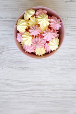 Mini meringues Beyaz ahşap arka plan, havai görünümü üzerinde pembe bir kase. Yukarıdan görünüm üst. Kopya alanı.