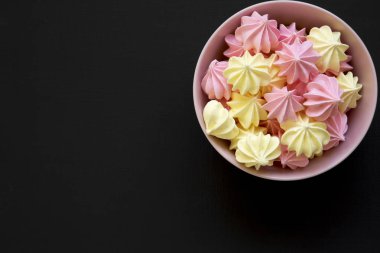 Mini meringues koyu arka plan, havai görünümü üzerinde pembe bir kase. Yukarıdan görünüm üst. Yakın çekim. Metin için yer.
