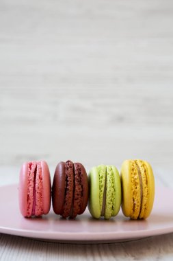 Beyaz ahşap zemin, yan görünüm üzerinde pembe plaka üzerinde tatlı macaroons. 