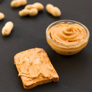 Fıstık ezmesi kase, karanlık bir arka plan, yan görünüm üzerinde unshelled fıstık. Yakın çekim.