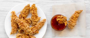 Baharatlı tavuk soslu beyaz plaka üzerinde beyaz ahşap yüzeye, havai görünümü şeritler. Yukarıdan, üstten görünüm düz yatıyordu. Yakın çekim.