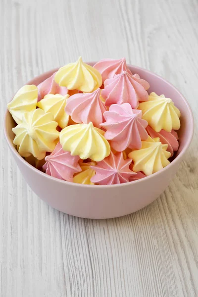 Mini meringues Beyaz ahşap bir masa yan görünüm üzerinde pembe bir kase. Portre.