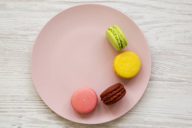 Tatlı ve beyaz ahşap yüzey, en iyi görünümü üzerinde pembe bir plaka üzerinde renkli Bademli kurabiye. Portre. 