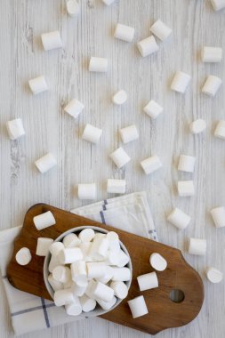 Beyaz ahşap arka plan, havai görünümü üzerinde rustik ahşap tahta üzerinde bir kasede kabarık Marshmallow. Yukarıdan, üstten görünüm düz lay.