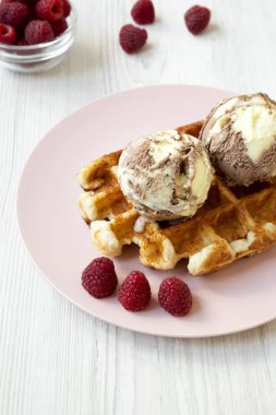 Dondurma ve ahududu pembe plaka, yan görünümü ile geleneksel Belçika waffle. Beyaz ahşap masa. Yakın çekim.