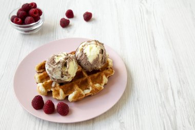 Dondurma ve ahududu pembe plaka, yan görünümü ile geleneksel Belçika waffle. Beyaz ahşap arka plan. Kopya alanı.