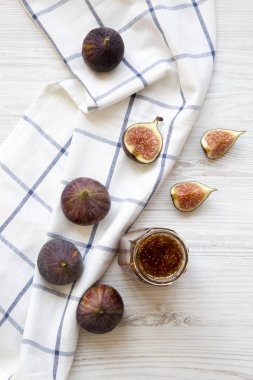 Beyaz ahşap masa, havai görünümü üzerinde taze incir ve incir reçeli cam kavanoz. Gelen yukarıdaki üstten görünüm. 