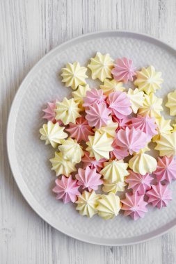 Beyaz ahşap yüzey üzerinde gri plaka üzerinde mini meringues yukarıdan görüntüleyin. Düz yatıyordu, genel gider, en iyi görünümü.