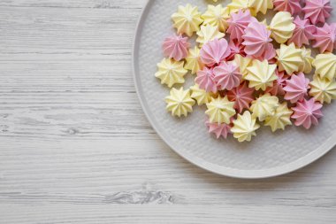Mini meringues Beyaz ahşap arka plan, havai görünümü üzerinde gri plaka üzerinde. Yukarıdan, üstten görünüm düz yatıyordu. Kopya alanı.
