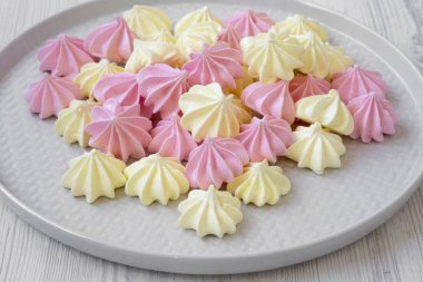 Mini meringues Beyaz ahşap arka plan, yan görünüm üzerinde gri plaka üzerinde. Portre.