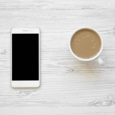 Smartphone ve latte havai görünümü beyaz tahta masada. Yukarıdaki üzerinden düz lay.