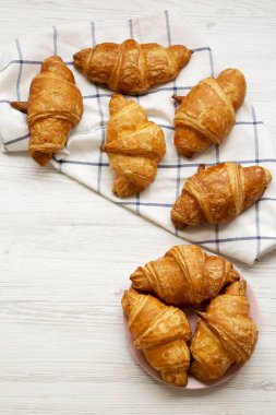 Beyaz ahşap masa, havai görünümü üzerinde altın kabuk ile taze kruvasanlar. Yukarıdan, lay düz. Kopya alanı.