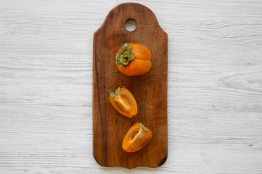 Beyaz ahşap masa, üstten görünüm üzerinde bir kesme tahtası üzerinde taze Trabzon hurması. Düz, tepegöz, yukarıdan yatıyordu. Kopya alanı.