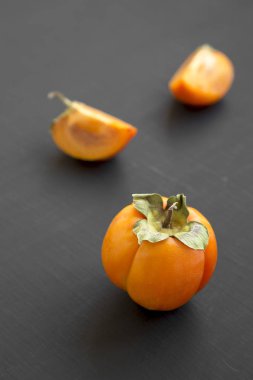 Siyah arka planda, yan görünüm taze Trabzon hurması. Portre. Seçici odak.