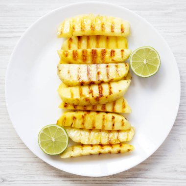 Ananas dilimleri ile kireç beyaz plaka üzerinde beyaz ahşap yüzey, havai görünümü üzerinde ızgara. Yaz yiyecek. Aperatif için fikir. Yukarıdan, lay düz.