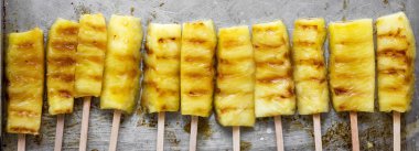 Izgara ananas üstten görünüm üzerinde bambu tepsi üzerinde sopa. Yakın çekim. Düz yatıyordu, ek yükü.