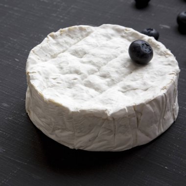 Koyu arka plan, yan görünüm üzerinde yaban mersini ile camembert peyniri. Yiyecek şarap için. Süt üretimi. Portre.