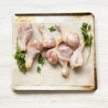 Çiğ çiğ tavuk ayakları üzerinde bir fırın yaprak kağıt tepsisindeki Beyaz ahşap arka plan, üstten görünüm üzerinde. Yakın çekim.